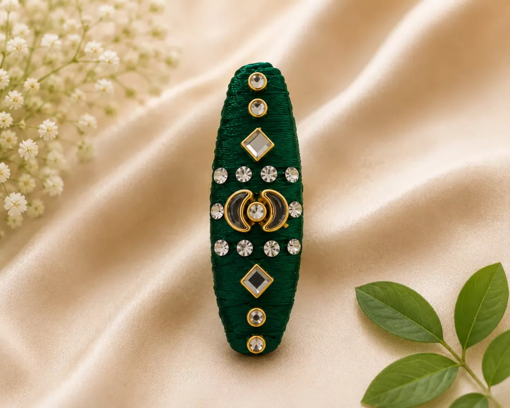 Emerald handmade thread saree pin with decorative detailing.
